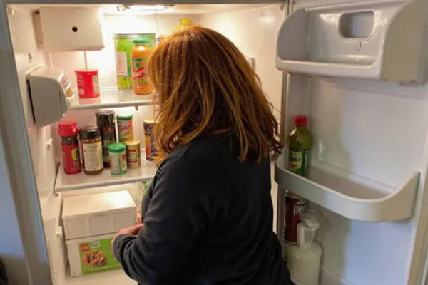 Claire Aldington, a fictional character, standing in front of an open fridge, surrounded by snacks and condiments. Never in her life would she have wondered: Does GLP-1 Stop Food Noise?